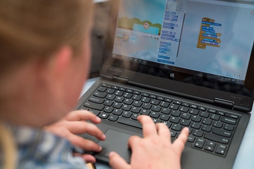 Child with a laptop. Screen shows Scratch.